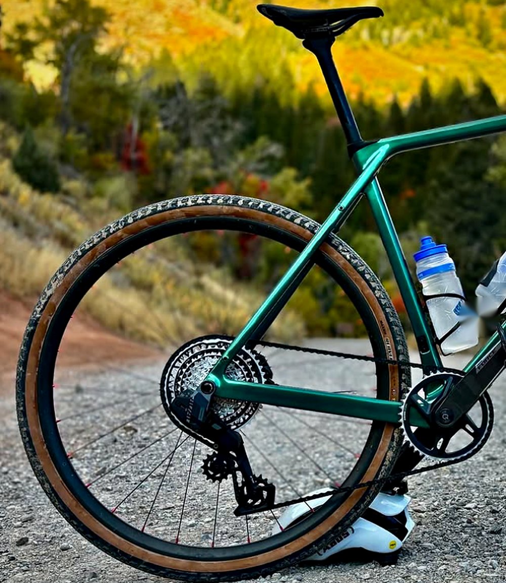 Spry Pyxis gravel bike on a dirt road with autumn colour behind