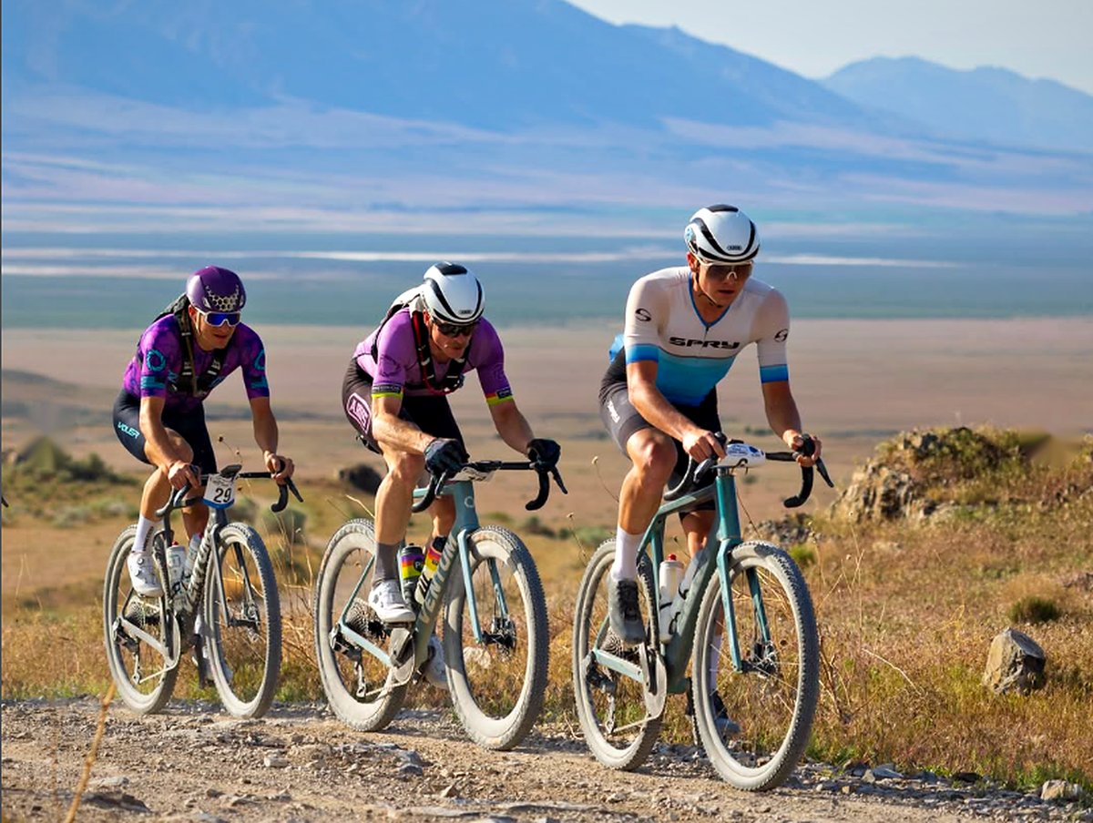 Three gravel racers climbing a dirt road, a Spry Pyxis leading